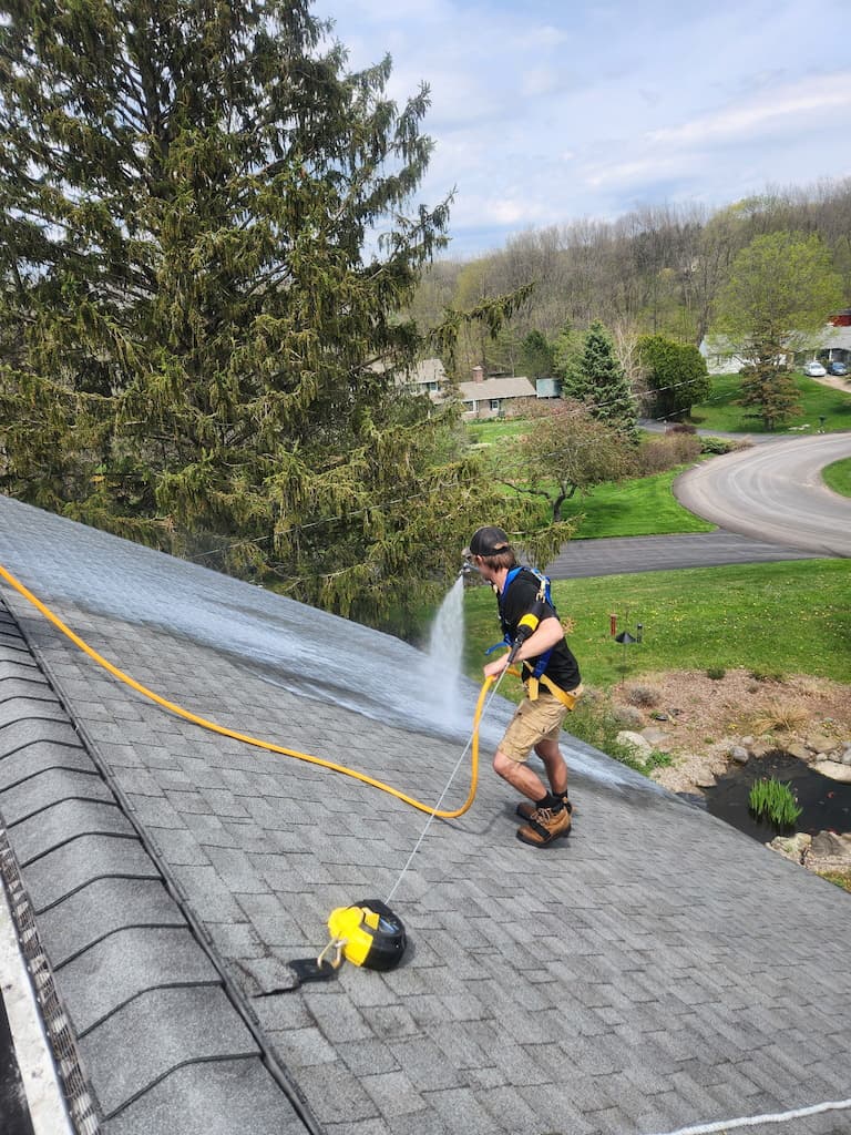 Technician of Roof Maxx of North Syracuse, NY applies roof maxx treatment on a roof