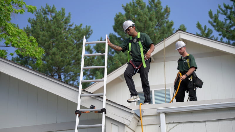 Two Roof Maxx dealers standing on a customer's roof