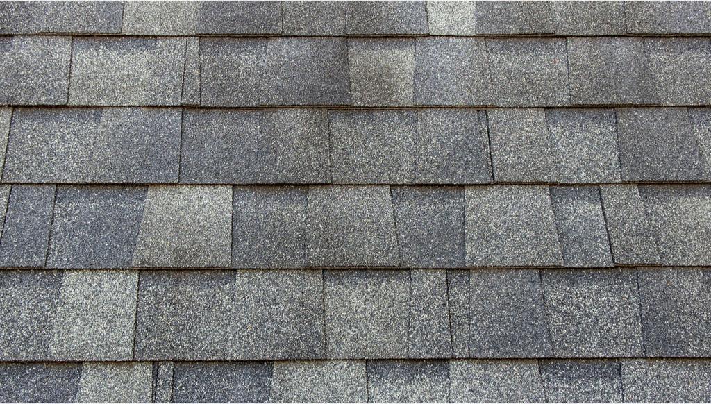 Close-up shot of bruised, hail-damaged asphalt shingles on an asphalt roof