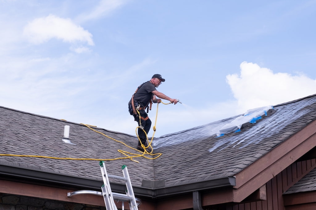 Roof Maxx professional spraying roof with solution that acts as natural fungicide to prevent moss, mold, and algae growth