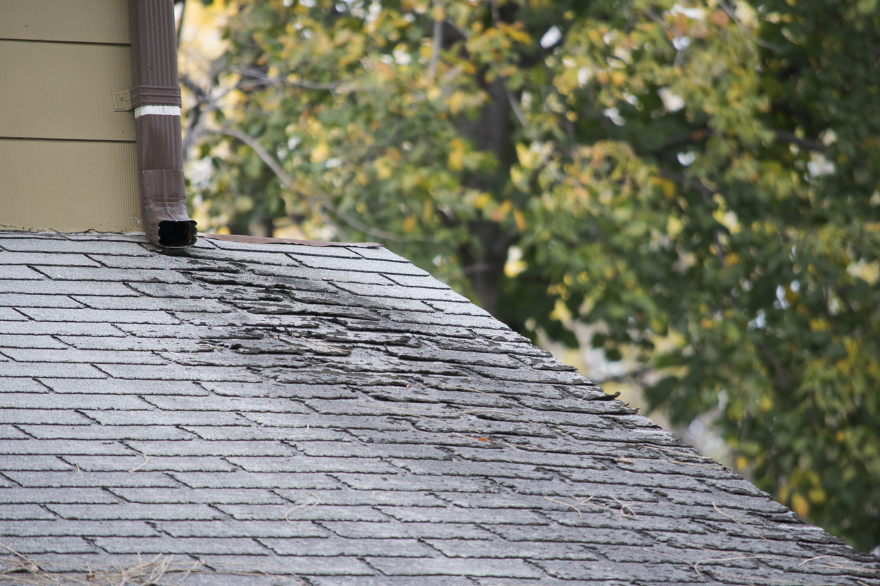Damaged roof shingles on residential house.