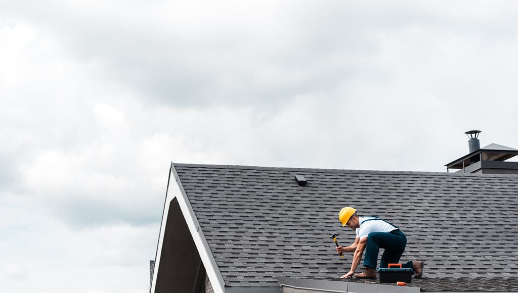 A roofer installs new shingles on a customer's roof