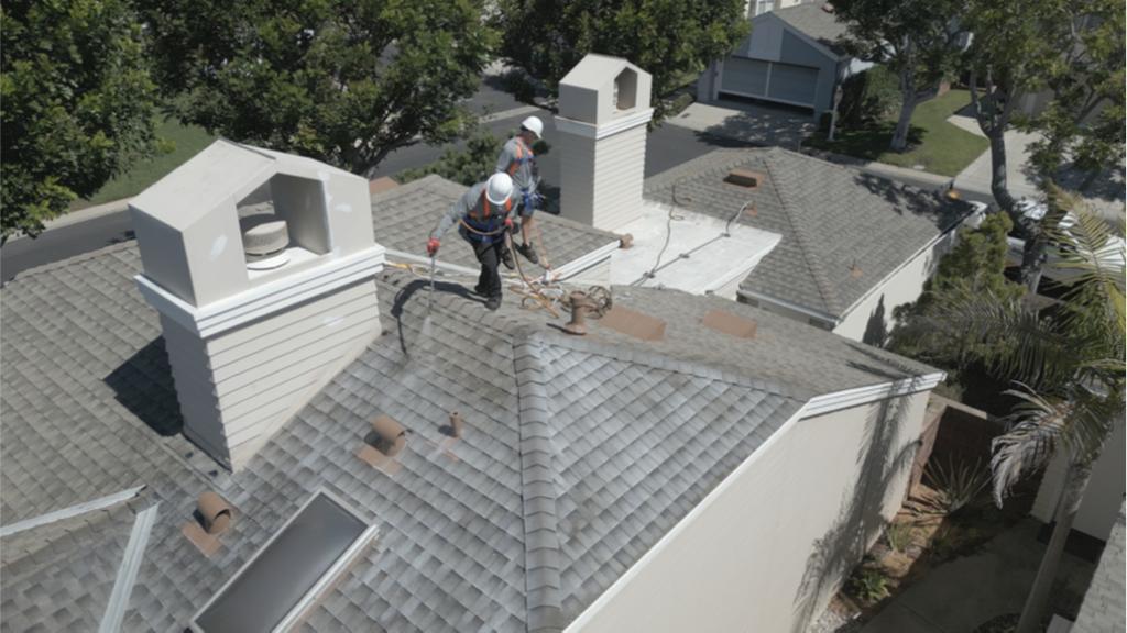 Two Roof Maxx dealers spray the treatment onto a customer's asphalt shingle roof