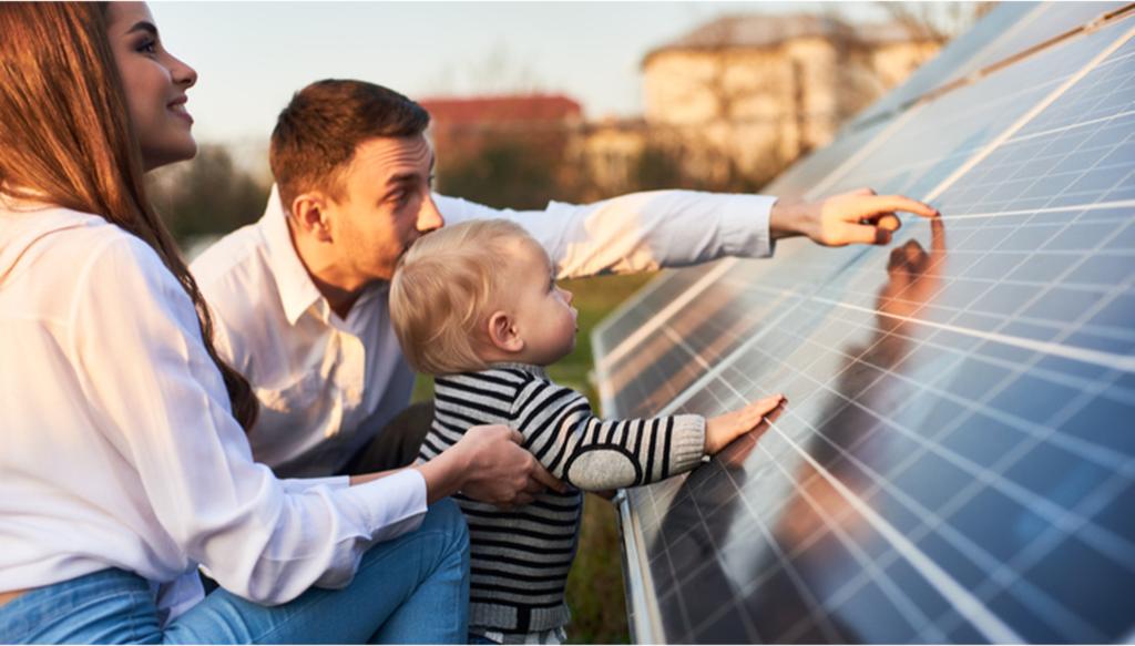 A family looks at a solar panel on the ground.