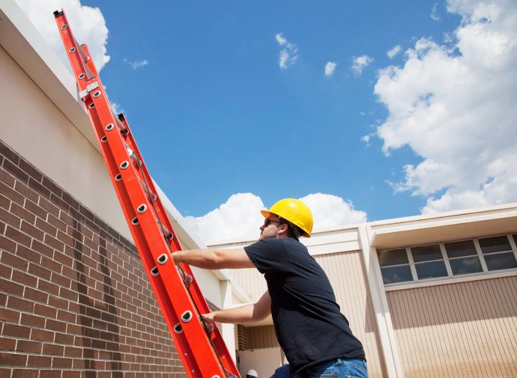 A roofer climbs a red ladder to access a roof