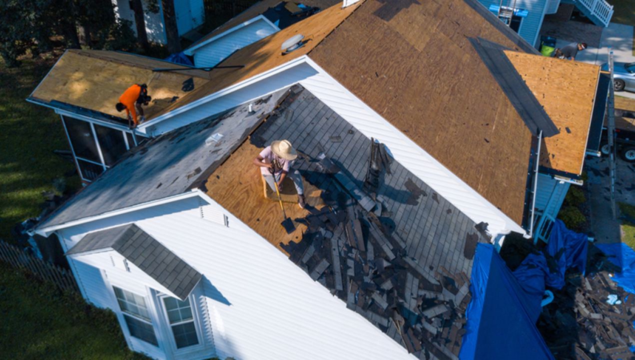 Roofers remove shingles from an asphalt shingle roof