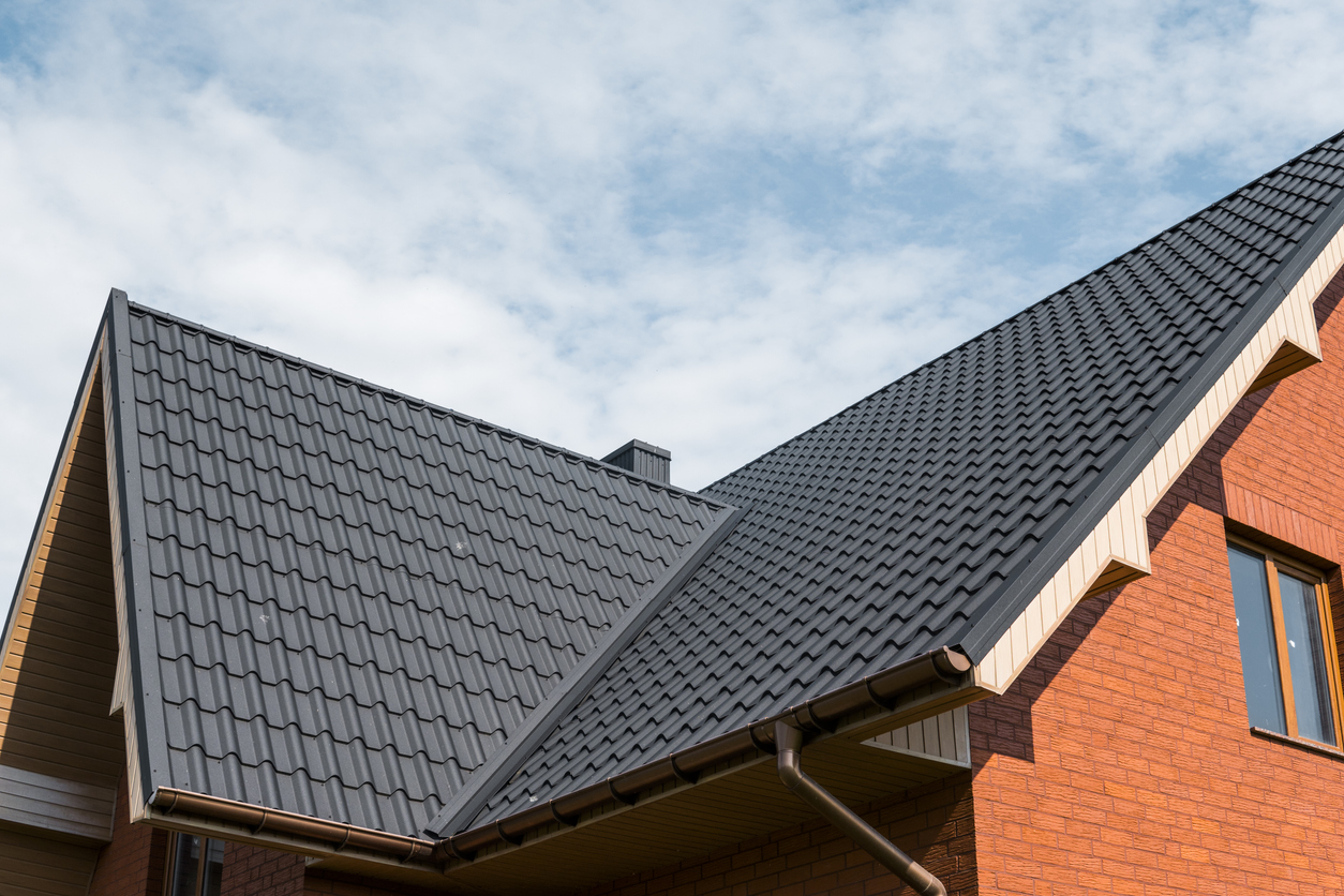 Side view of a roof with metal shingles on a red brick house