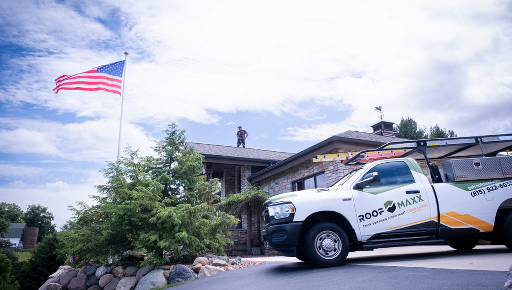 A dealer applies Roof Maxx to a customer's home behind a branded Roof Maxx truck.