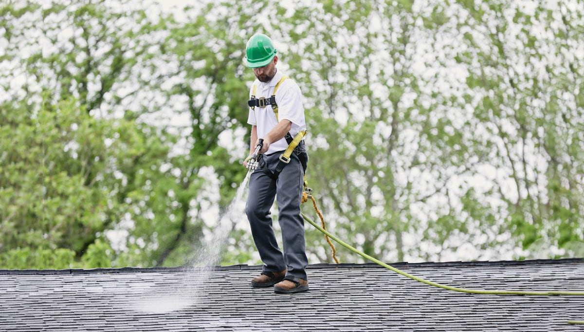 Roofing professional applying Roof Maxx treatment to asphalt shingle roof