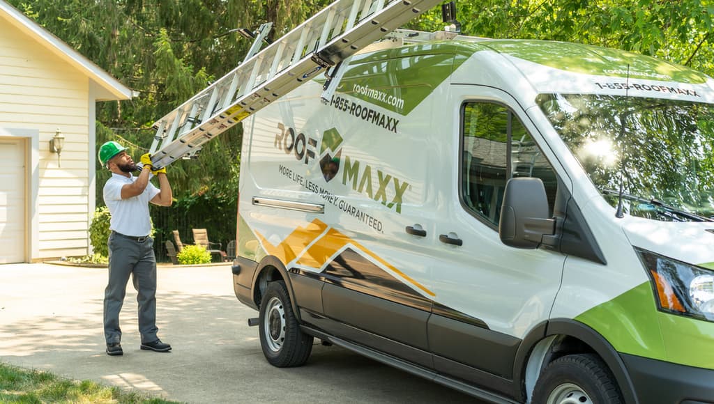 Side view of a dealer loading a ladder onto a Roof Maxx truck