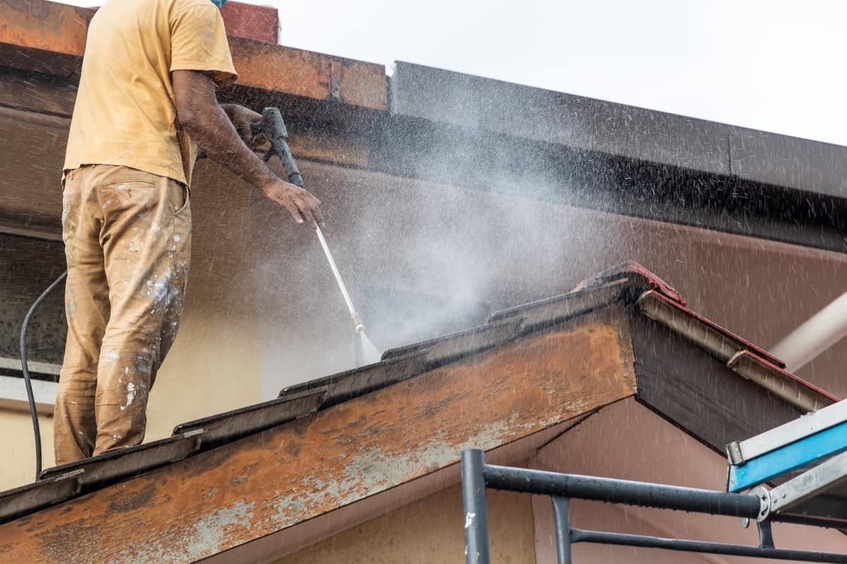 Homeowner using applicator to apply DIY spray to roof shingles