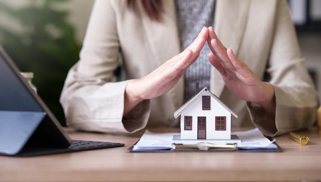 Woman protecting a small model of a house with her hands