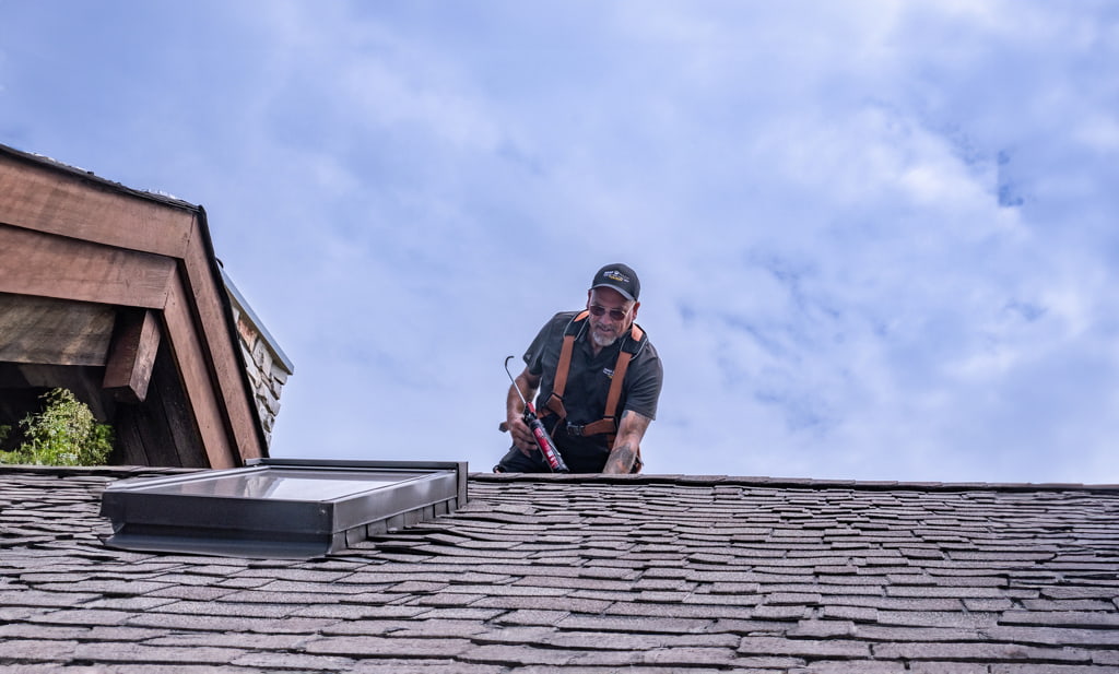 Professional working on roof of US home to rejuvenate shingles with Roof Maxx treatment