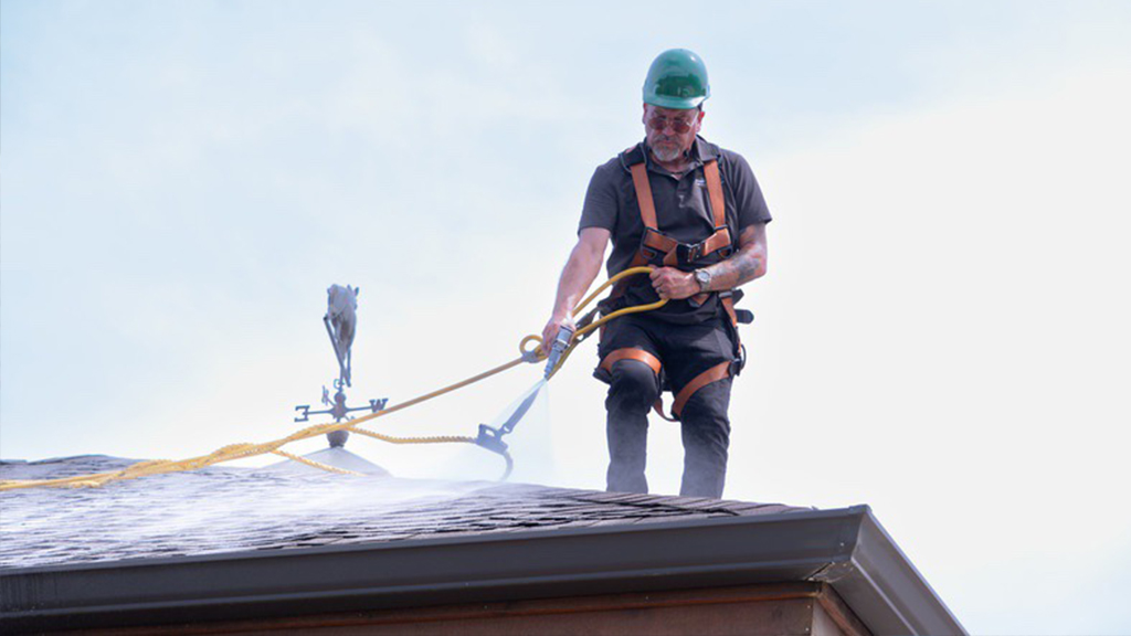 Roof Maxx worker applying roof rejuvenation to residential home