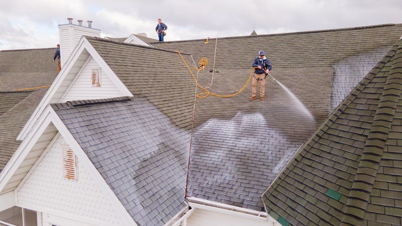 Roof Maxx professional treating asphalt shingles on roof of home to help extend their lifespan,