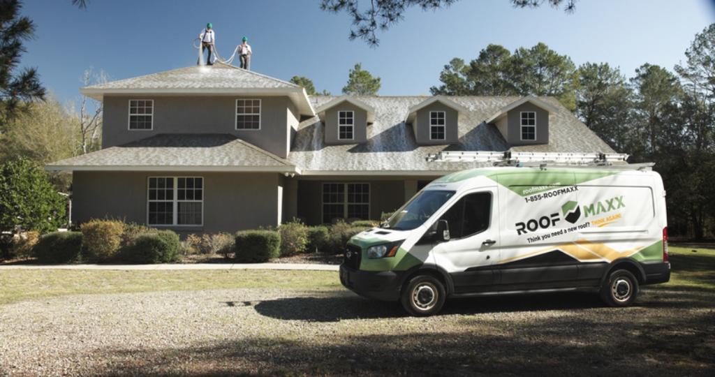 Roof Maxx van outside of home with applicators working on roof