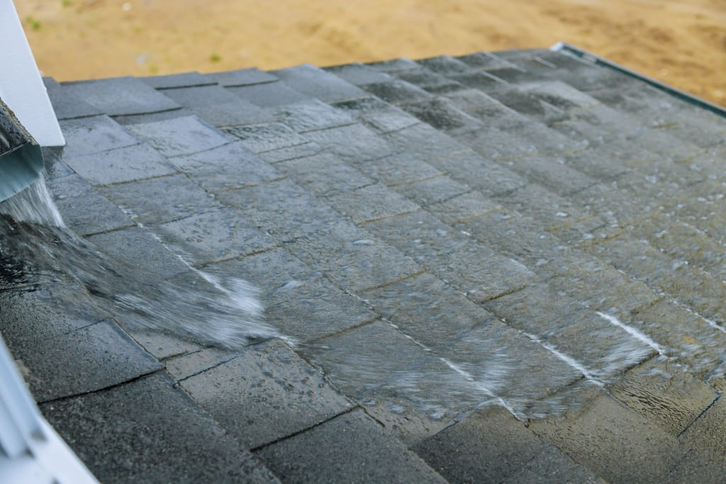 Asphalt shingle roof in heavy downpour to represent leak risk.