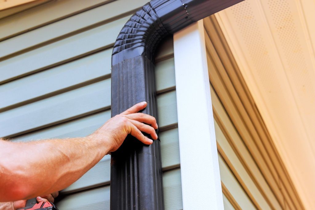 Contractor installing rectangular downspout on residential home