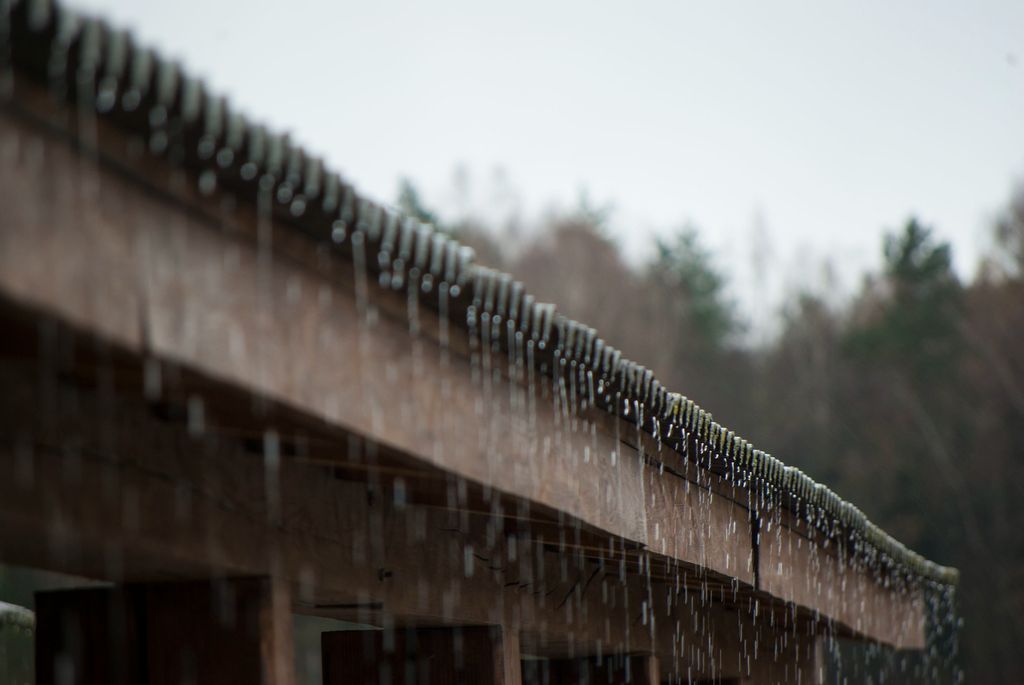 Rain falling off edge of roof on home