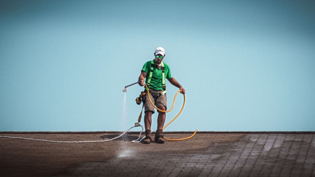 Roof Maxx professional applying treatment to asphalt shingle rooftop