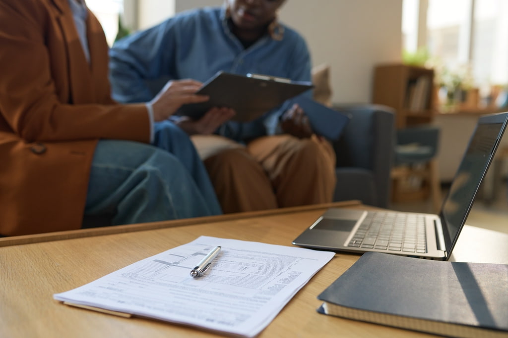 Homeowners going through insurance policy with copy next to laptop on table nearby