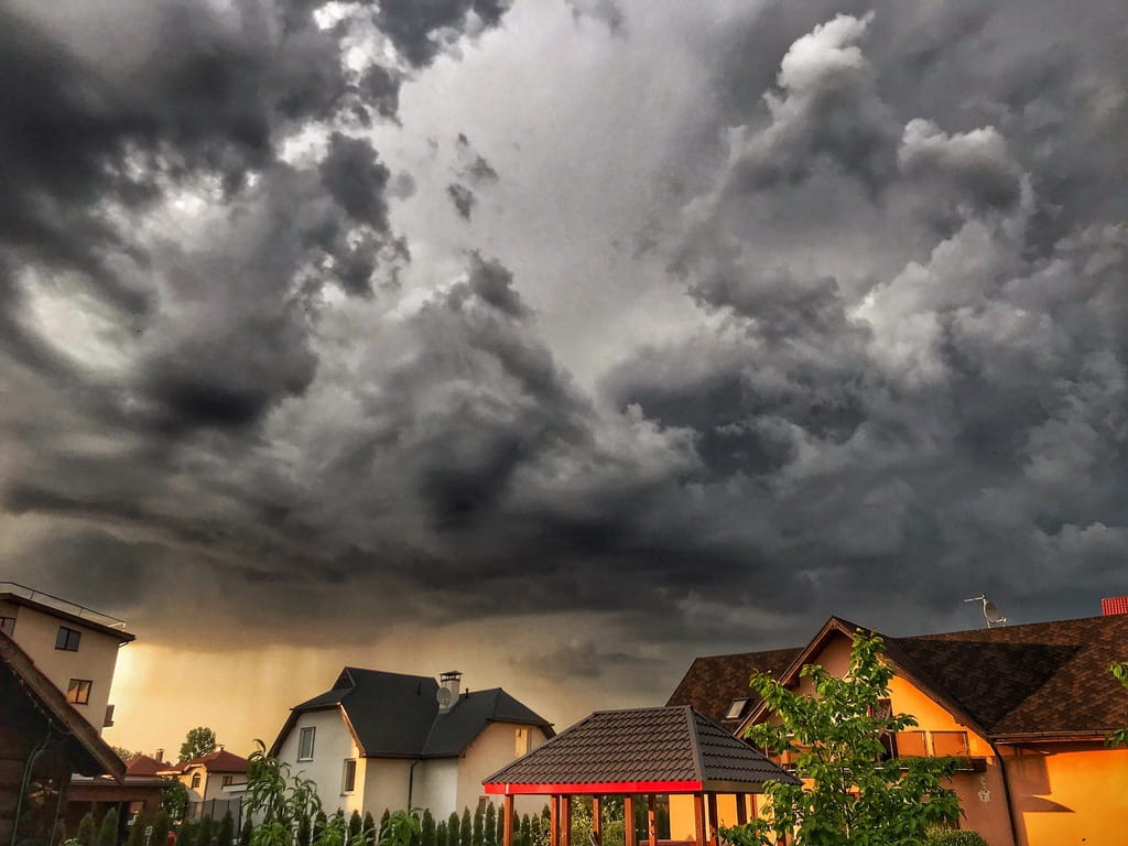 Homes under grey sky before storm to represent threat of roof leaks and value of insurance coverage