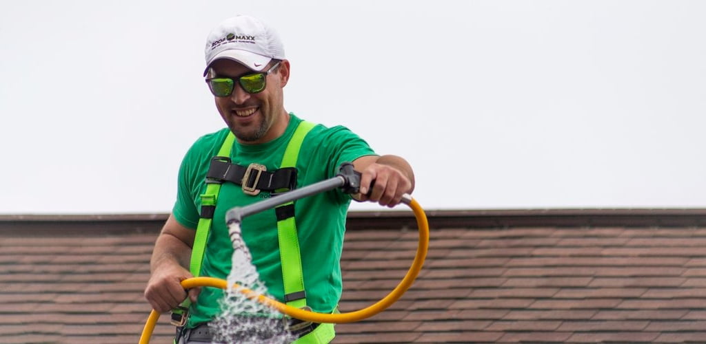 Roof Maxx professional smiling with applicator on top of residential shingle roof