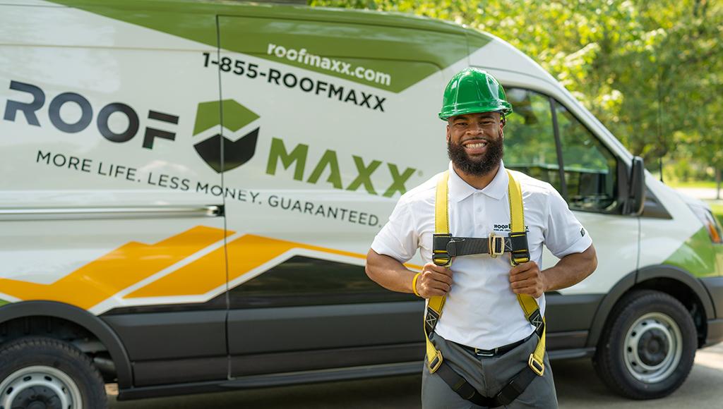 A Roof Maxx dealer smiling, ready to help a customer, in front of a branded Roof Maxx van.