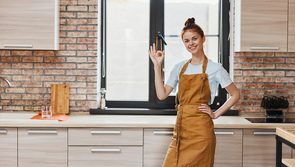 A woman stands in the kitchen smiling--her window is totally ok!