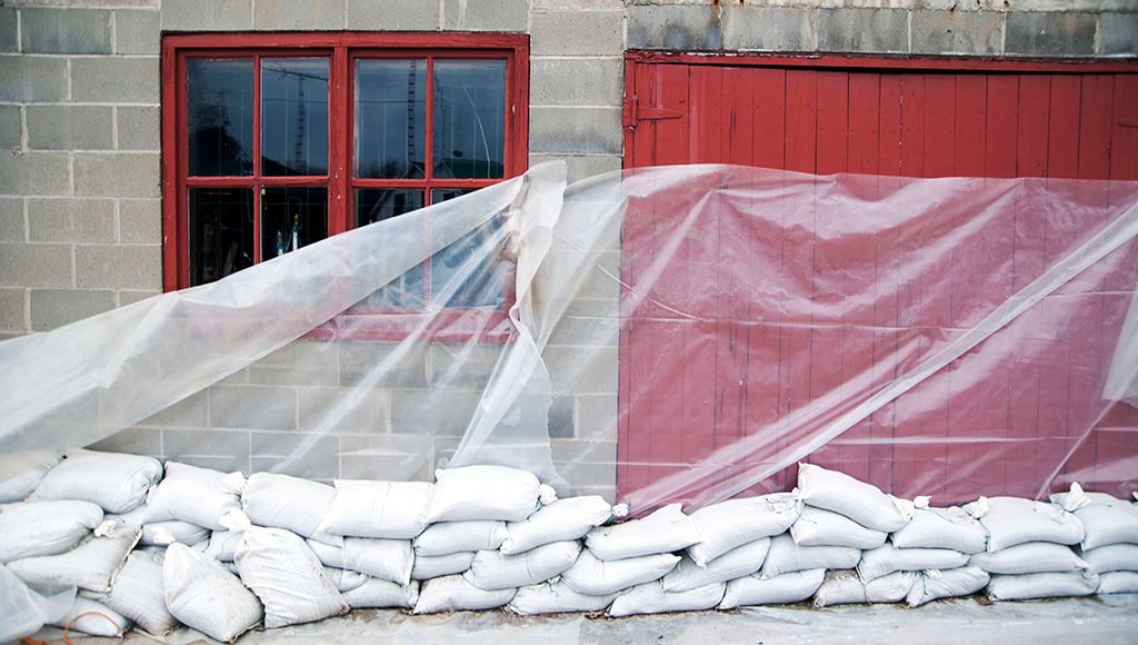 Nylon sandbags and a tarp shore up a building in a flood zone during a hurricane.