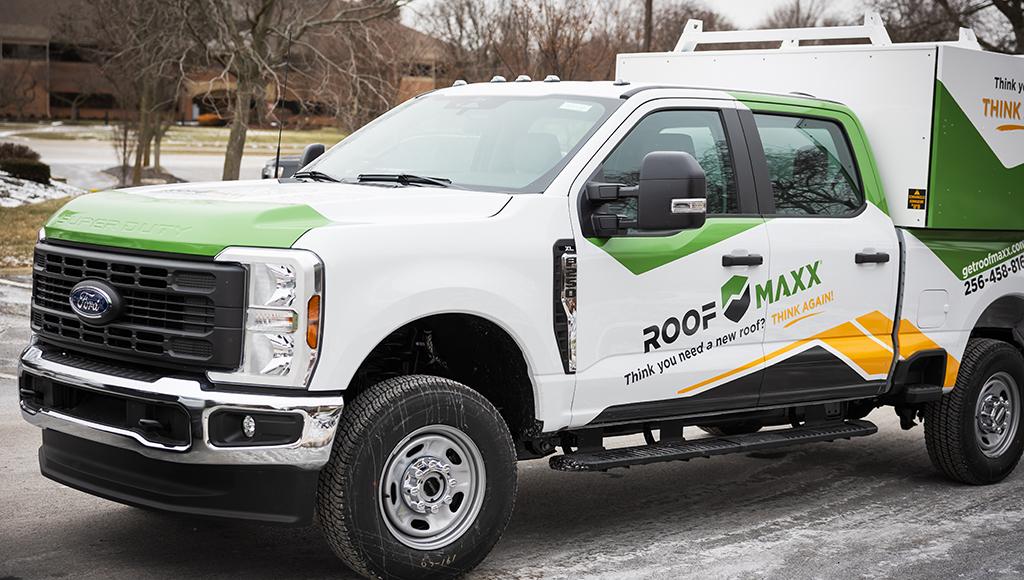 A Roof Maxx truck pulls up in front of a customer's home.
