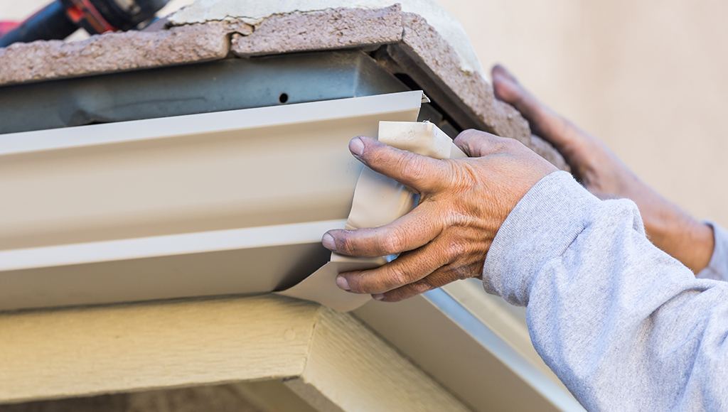A roofer installs standard 5-inch gutters.