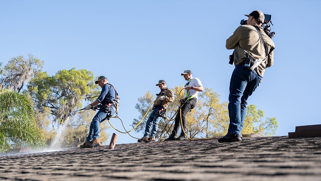 Roof Maxx professionals applying solution to asphalt shingle roof