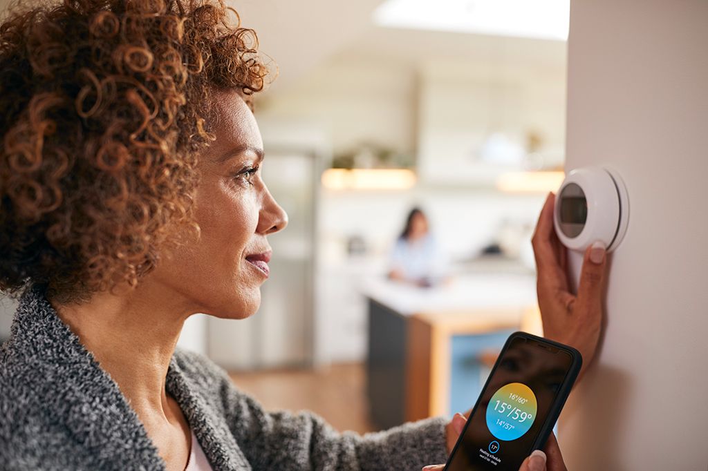 A woman syncs her phone to the thermostat in her kitchen