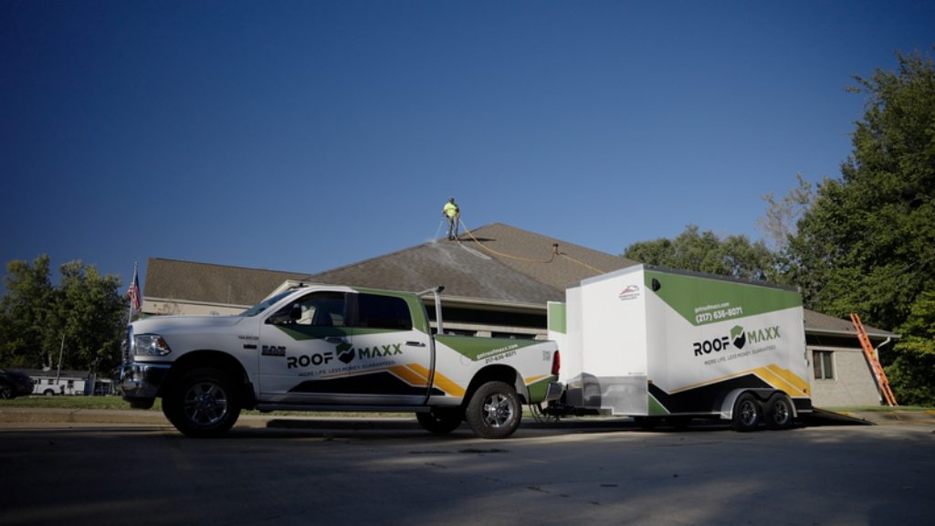 Roof Maxx truck parked outside building with professional spraying solution on asphalt shingle rooftop