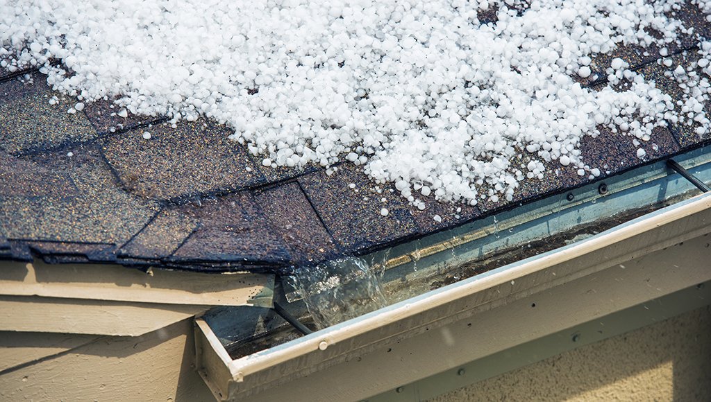 Hailstones melting on an asphalt shingle roof after a storm