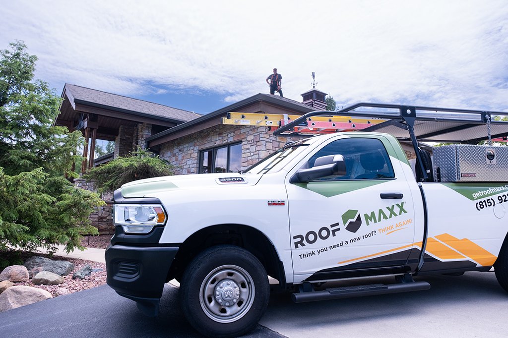 Roof Maxx professionals standing on home with branded truck parked on street below