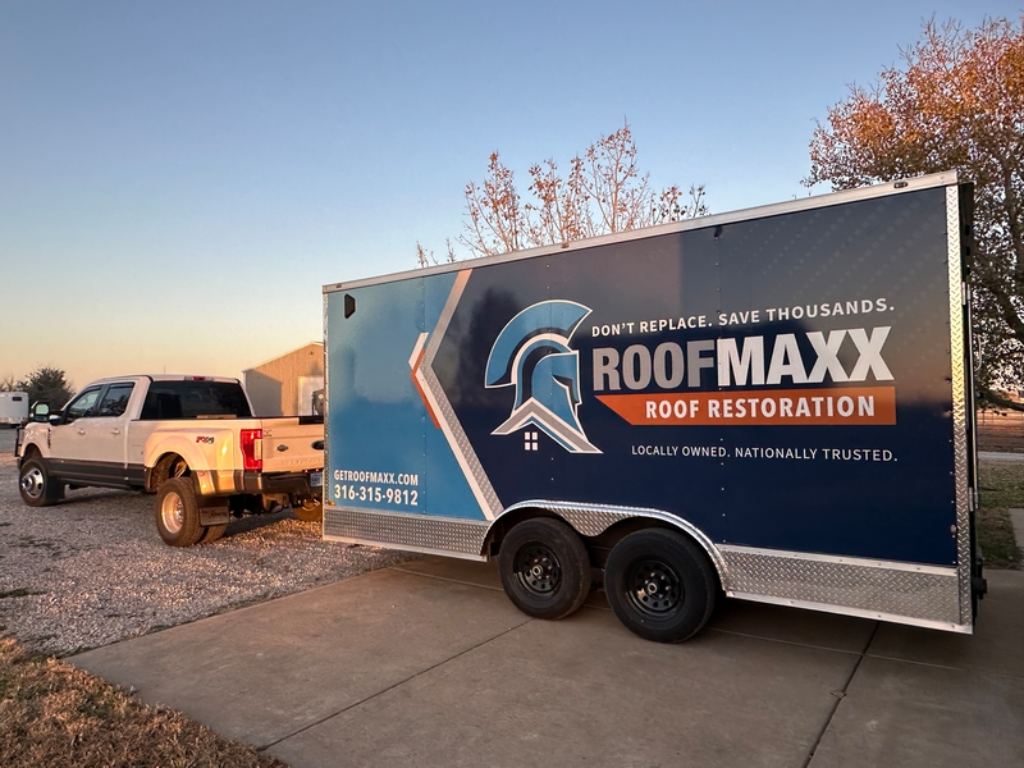 A white truck pulling a blue branded Roof Maxx trailer