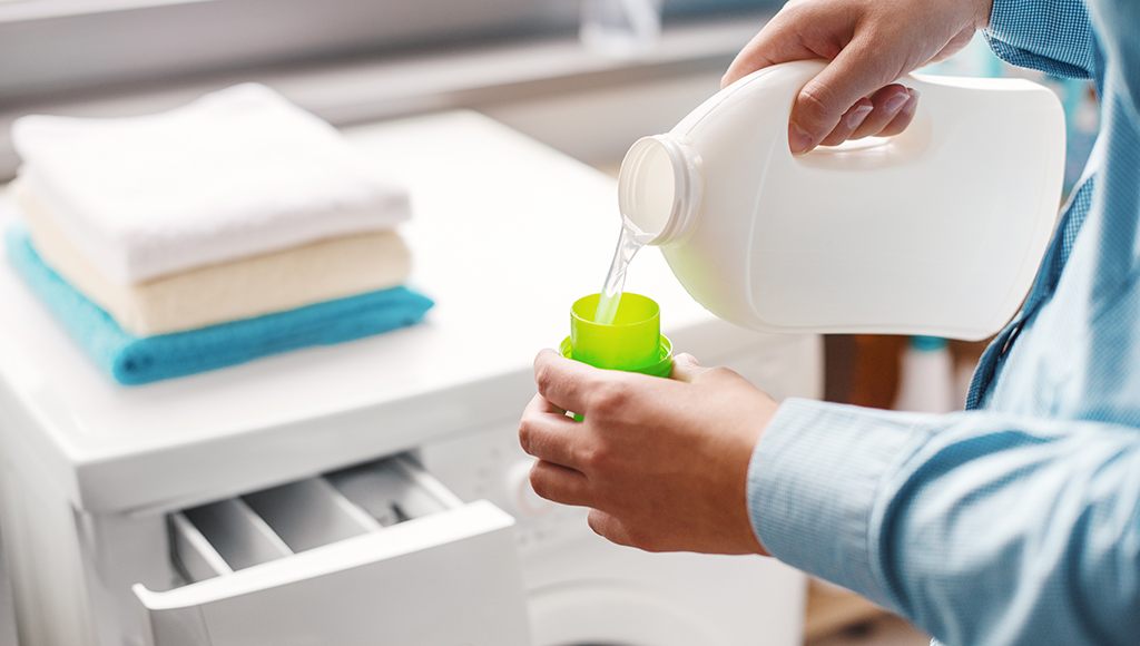 A woman adds dye-free laundry detergent to her washer.