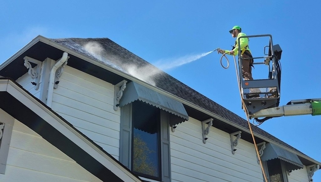 Contractor applying Roof Maxx with sprayer from picker unit