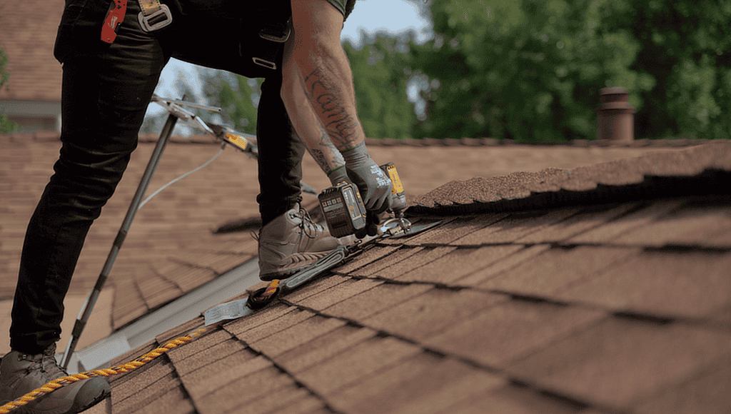 Roofer driving shingles into a low-slope asphalt shingle roof.