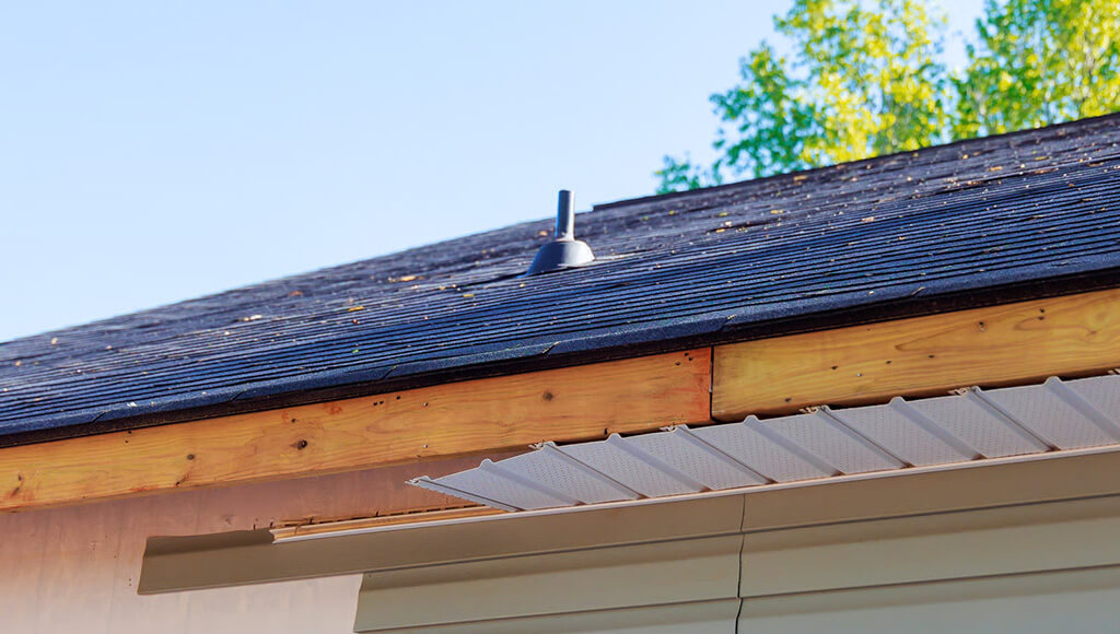Angled shot of an asphalt shingle roof edge, including flashing and soffits.