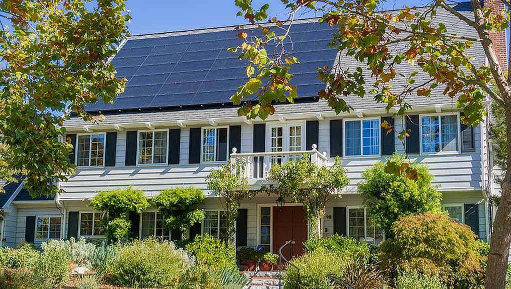 A side view of a beautiful residential home with solar panels and a black asphalt roof.
