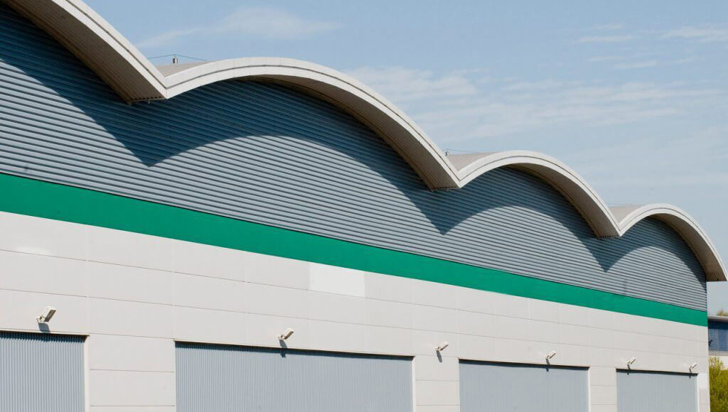 A curved roof with multiple arches on a commercial garage building with corrugated metal siding.