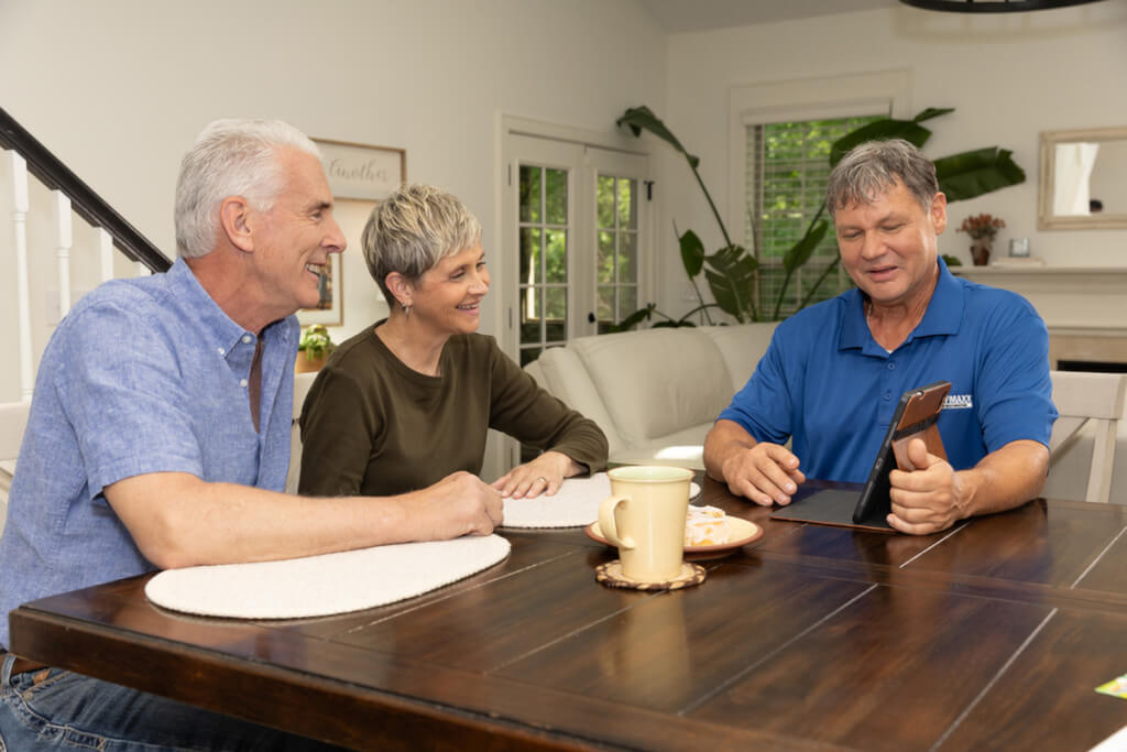 A Roof Maxx dealer walks two homeowners through the basics of roof restoration at a kitchen table.