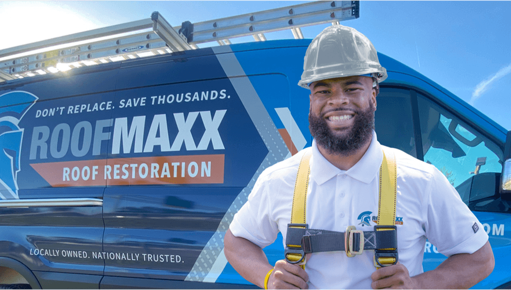 A Roof Maxx dealer from Columbus, Ohio, smiles in front of a blue branded Roof Maxx van.