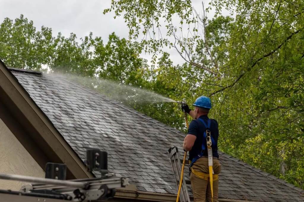 Two Roof Maxx dealers stand on a customer's asphalt shingle roof.