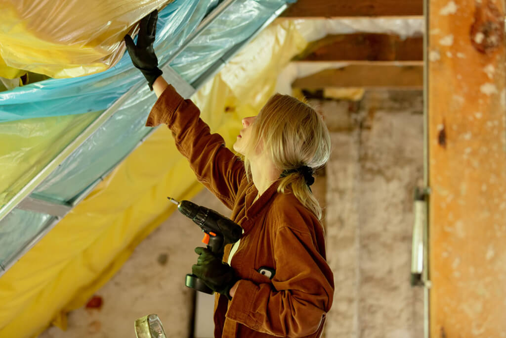 A woman carefully checks the insulation in the attic of her cold climate home.