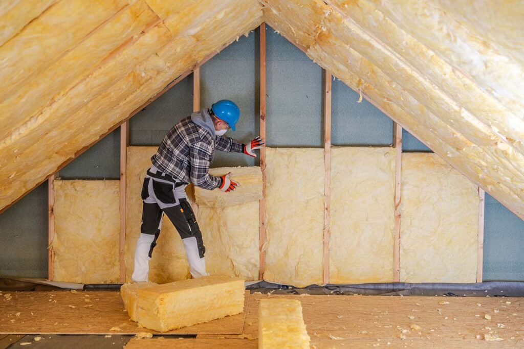 A worker installs fresh insulation in a customer's attic.