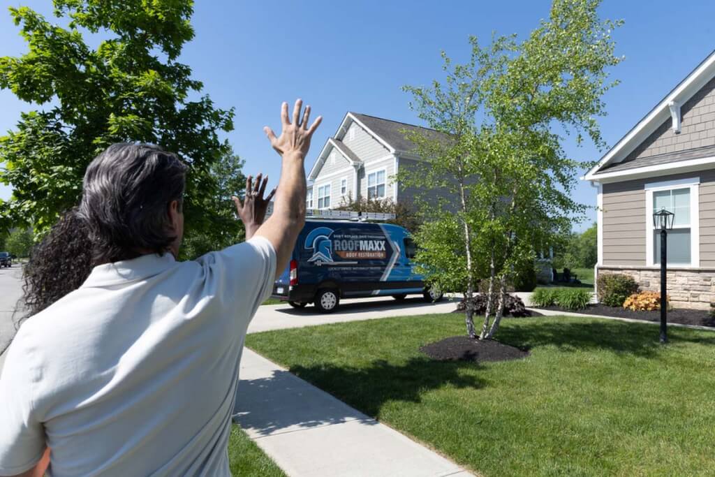 Two homeowners wave goodbye to Roof Maxx before the dealer drives off.